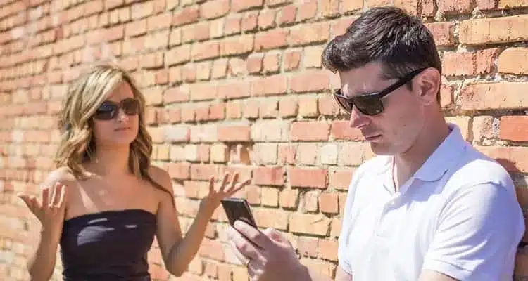 angry man looking phone displeased young woman up her hands front wall background focus man.jpg